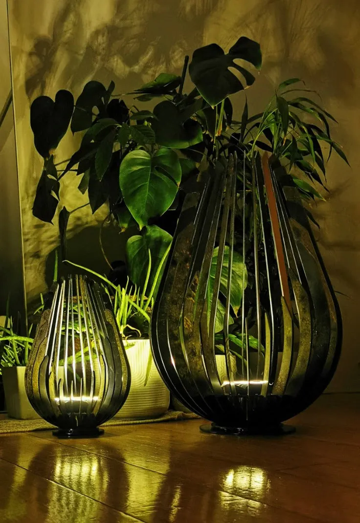 Corten solar lanterns glowing at night among plants