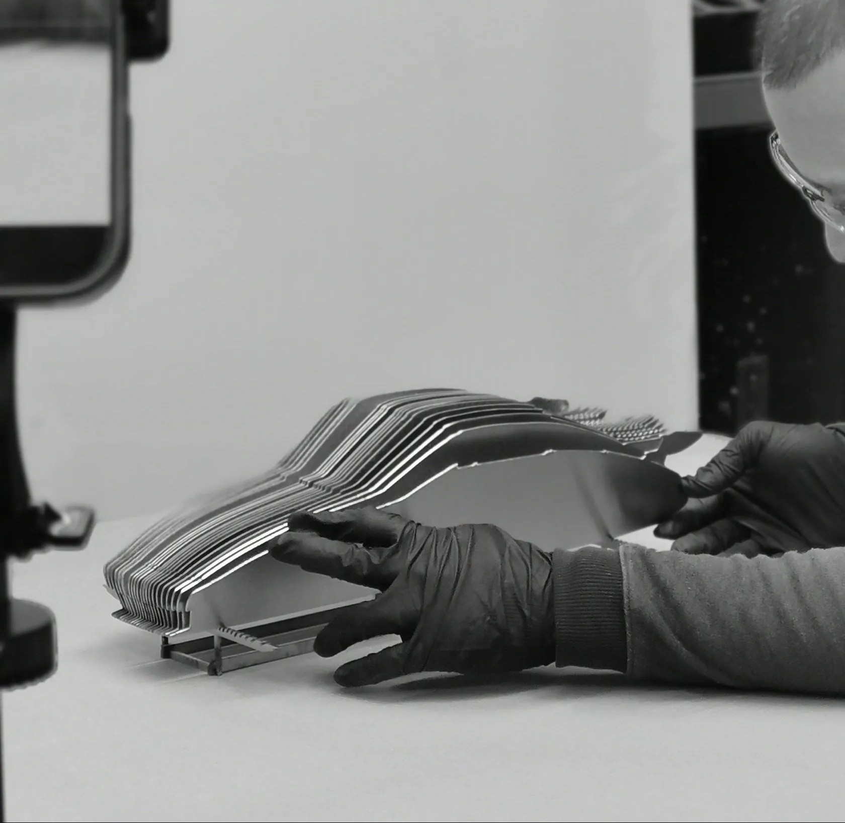 Hands assembling a layered steel sculpture in the DecoMetal workshop